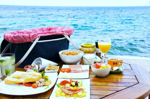 a table with food and drinks next to the ocean at Scuba Lodge & Suites in Willemstad