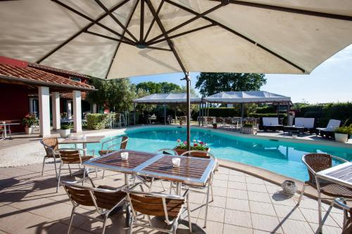 a table and chairs with an umbrella next to a pool at Hotel La Posta di Torrenova in Orbetello