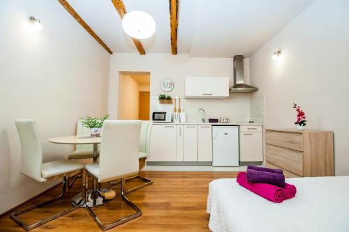 uma cozinha com armários brancos e uma mesa com um saco rosa em Sebenicum Apartments em Šibenik
