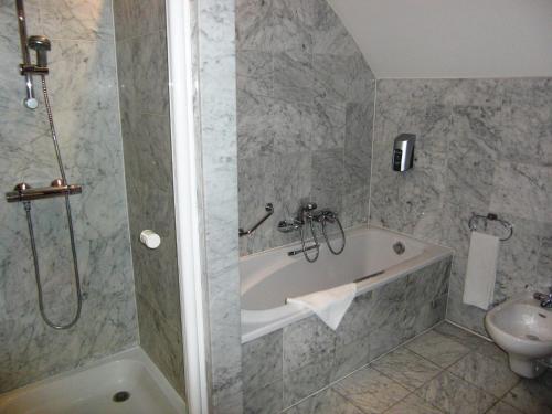 a bathroom with a bath tub and a sink at Golden Tulip Hotel de’ Medici in Bruges