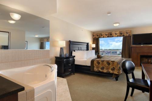 a hotel room with a bed and a bath tub at Ramada by Wyndham Wainwright in Wainwright