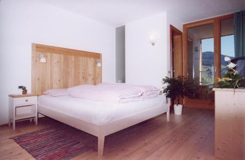 サン・ヴィジリオ・ディ・マレッベにあるAl Cargàの白いベッド1台(木製ヘッドボード付)が備わるベッドルーム1室が備わります。