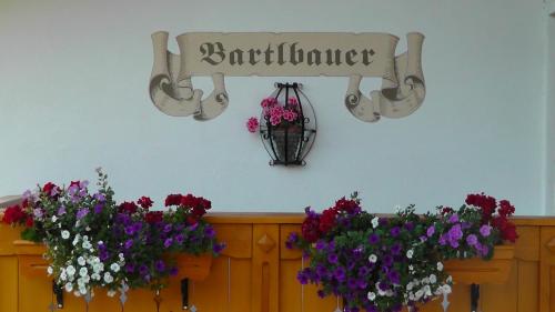 a sign on a wall in front of a vase of flowers at Pension Bartlbauer in Ramsau am Dachstein