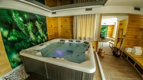 eine Whirlpool-Badewanne in einem Zimmer mit tropischem Wandbild in der Unterkunft Hotel Han Bjelašnica in Bjelašnica