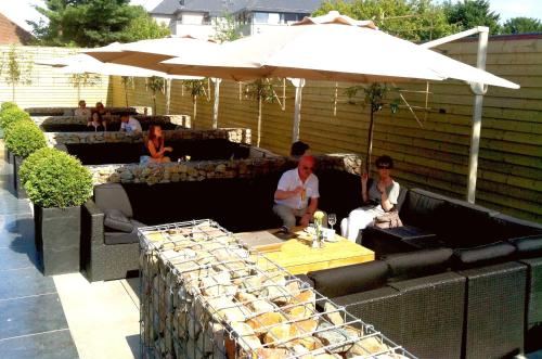 a group of people sitting on a patio under an umbrella at Hotel Brasserie Den Engel in Baarle-Nassau