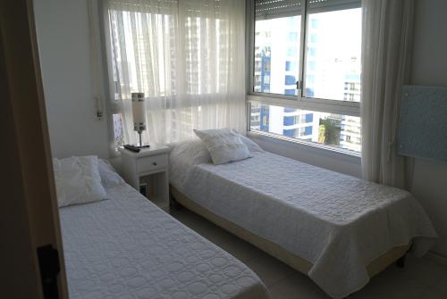 2 camas en una habitación con 2 ventanas en Torre Long Beach, en Punta del Este