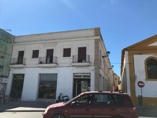 a red van parked in front of a white building at Apartamentos Centro 1 El Puerto de Santa Maria in El Puerto de Santa María