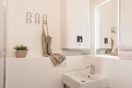 La salle de bains blanche est pourvue d'un lavabo et d'un miroir. dans l'établissement Appartements Avignon Centre, à Avignon