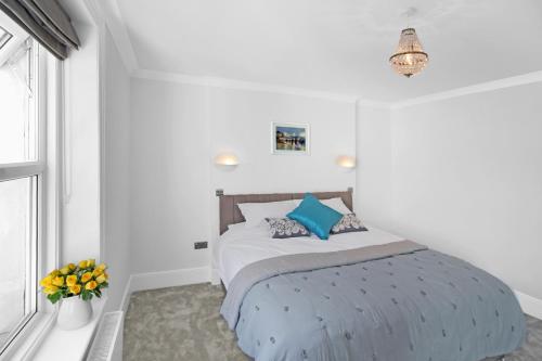 Un dormitorio con una cama con almohadas azules y una ventana en Ocean Outlook - Broadstairs Best!, en Broadstairs