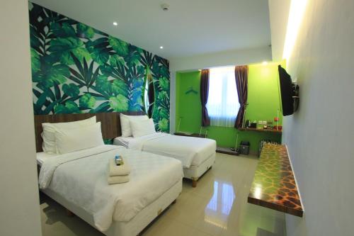 a hotel room with two beds and a couch at Uniq Hotel in Yogyakarta