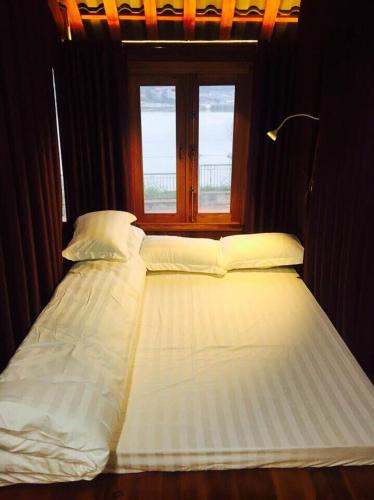 a bed with white sheets and pillows next to a window at Bac Ha Lake View in Bắc Hà