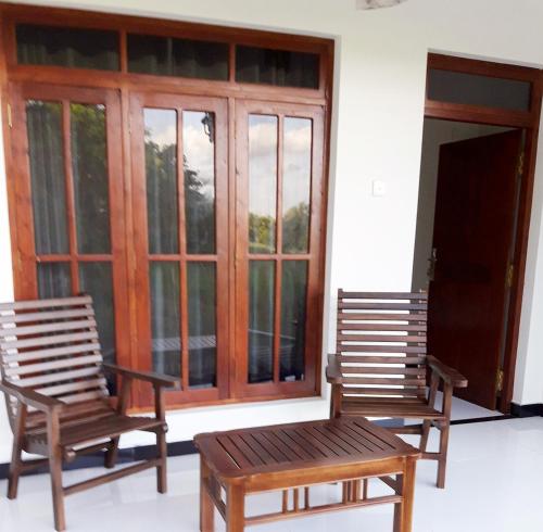 two wooden chairs sitting in front of a window at Sigiriya Paradise Inn in Sigiriya