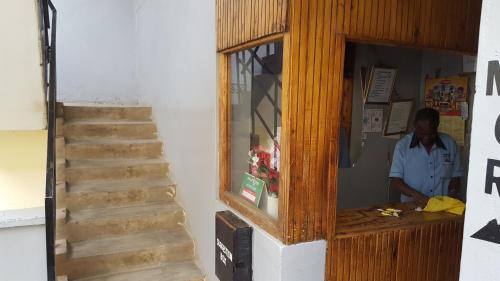 a man standing at a counter next to a staircase at Mona Lisa Guest House, Kisumu in Kisumu