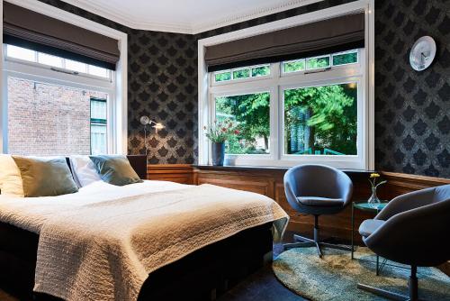 um quarto com uma cama, 2 janelas e uma cadeira em Guesthouse Villa Emmen em Emmen