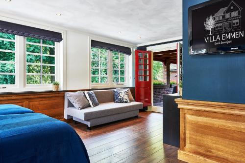 a bedroom with a couch and a tv in a room at Guesthouse Villa Emmen in Emmen