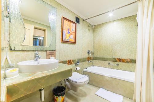 a bathroom with a sink and a toilet and a tub at Hotel Hillock in Mount Ābu