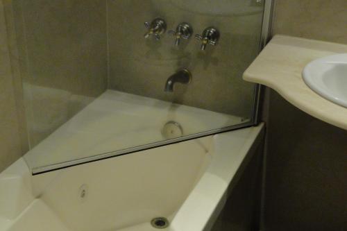 a bathroom with a shower with a sink and a tub at Hotel Amsterdam in Mar del Plata