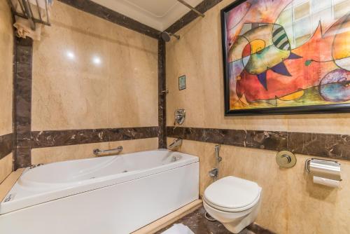 a bathroom with a tub and a toilet and a painting at Hotel Hillock in Mount Ābu