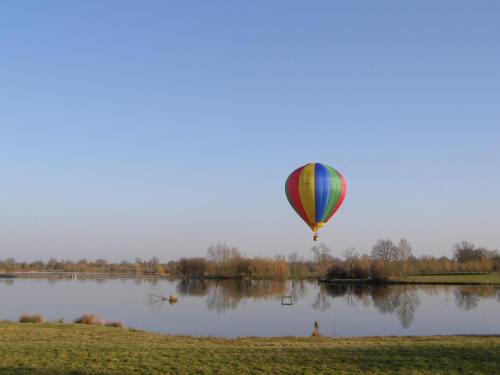 a hot air balloon flying over a lake at Pescalis Résidence Les Maisons du Lac in Moncoutant
