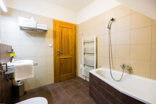 a bathroom with a tub and a toilet and a sink at Penzion U Barana in Trojanovice