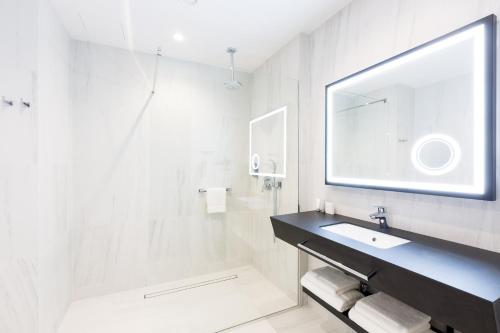 a white bathroom with a sink and a mirror at Grand Ascot Hotel in Kraków