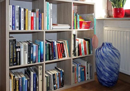 a book shelf filled with books next to a vase at Ferienwohnung Waldstraße in Waldsassen