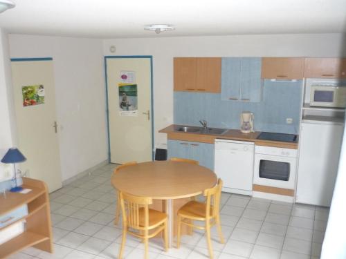 a kitchen with a table and chairs in a room at Pescalis Résidence Les Maisons du Lac in Moncoutant