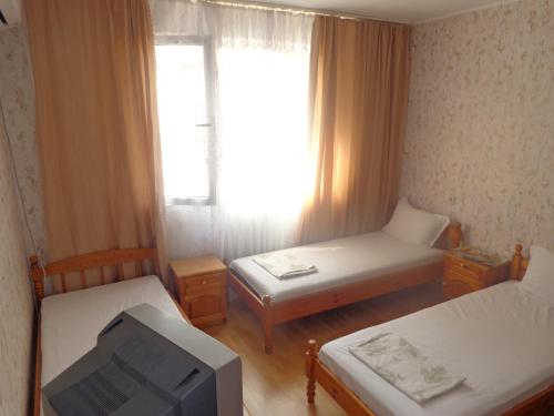 a small room with two beds and a television at Prometei in Burgas