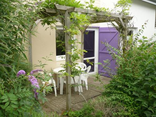 a pergola with a table and chairs in a garden at Pescalis Résidence Les Maisons du Lac in Moncoutant