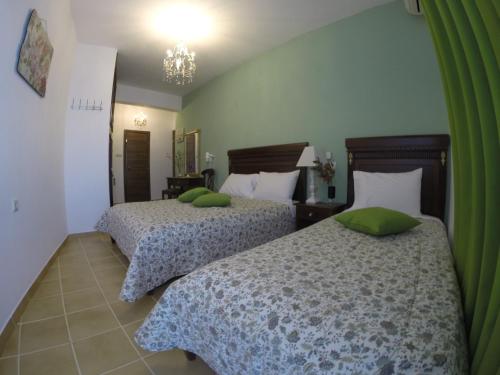 two beds with green pillows in a bedroom at Akrotiri Hotel in Neos Marmaras