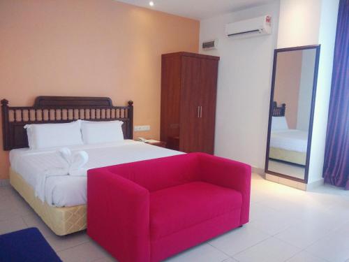 a bedroom with a large bed and a red chair at MNY Hotel & Resort in Pangkor