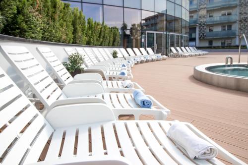 a row of white lounge chairs on a boardwalk at Hotel Aquarius SPA in Kołobrzeg