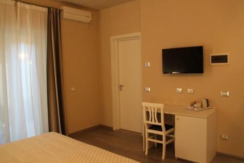 1 dormitorio con escritorio y TV en la pared en Il Viale b&b, en Pontedera