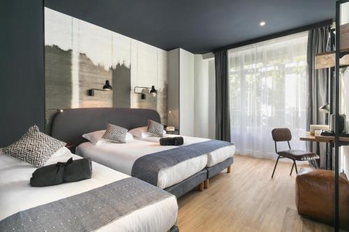 a hotel room with two beds and a chair at Hotel So’Co by Happyculture in Nice
