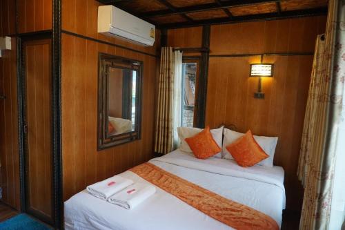 two beds in a room with wooden walls and a mirror at Mitaree Hotel 1 in Mae Sariang