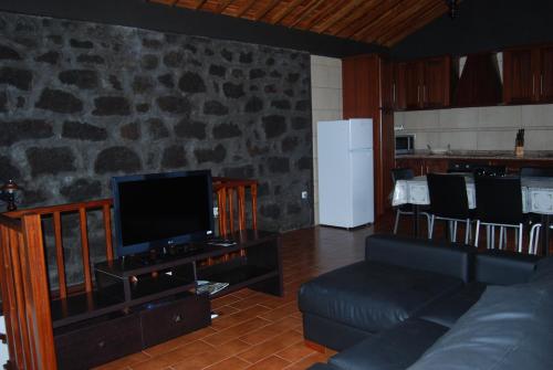 uma sala de estar com um sofá e uma televisão em Casa do Terreiro em Caminho de Cima