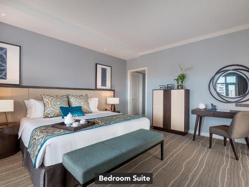 a bedroom with a bed with a table and a chair at Ascott Makati in Manila