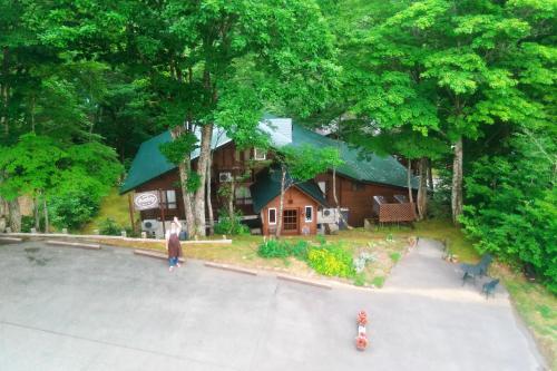 a woman standing in front of a wooden house at Pension Buddy in Kitashiobara