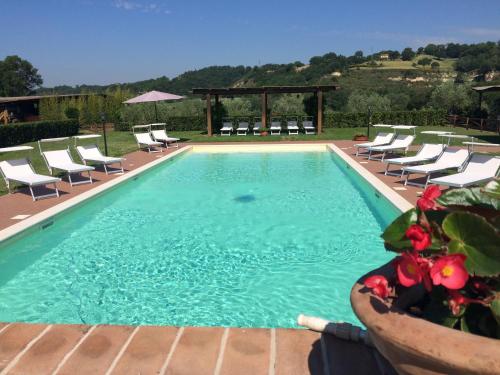a swimming pool with chairs and a gazebo at Podere Calledro in Narni