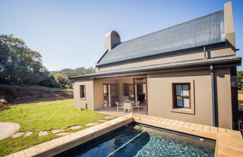 a house with a swimming pool in front of it at Botlierskop Bush Villas in Sandhoogte