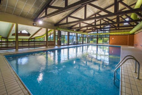 a large pool with blue water in a building at L'ESCANDILLE Village Vacances in Autrans