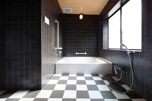 a bathroom with a white tub and a checkered floor at 宿屋 天空 in Asago