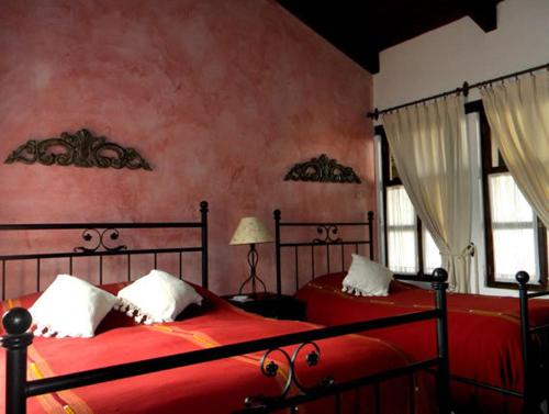 two beds in a bedroom with red walls and windows at Hotel Casa Madeleine B&B & Spa in Antigua Guatemala