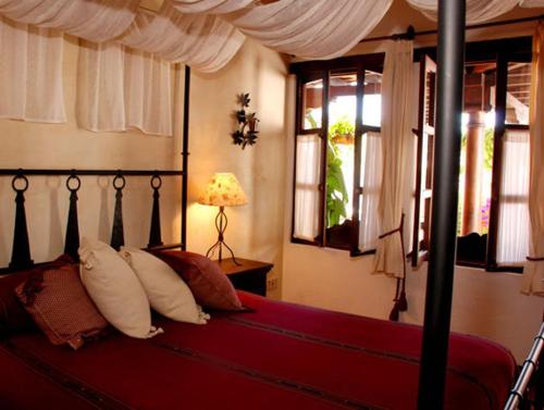 a bedroom with a bed with red sheets and pillows at Hotel Casa Madeleine B&B & Spa in Antigua Guatemala