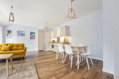 a living room with a table and chairs and a yellow couch at Dwie Sosny z sauną, Sun & Snow in Ustronie Morskie