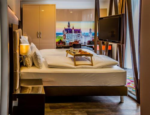 um quarto com uma cama grande e uma televisão de ecrã plano em Hotel Kreis Residenz München em Munique