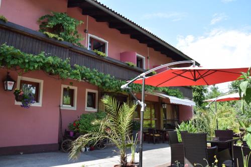 a building with an umbrella and tables and chairs at Frühstückspension Matheidl in Ferlach