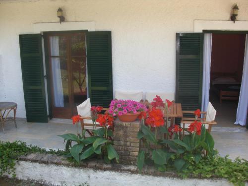 a porch with green shutters and flowers and a bench at Kahlua in Liapades