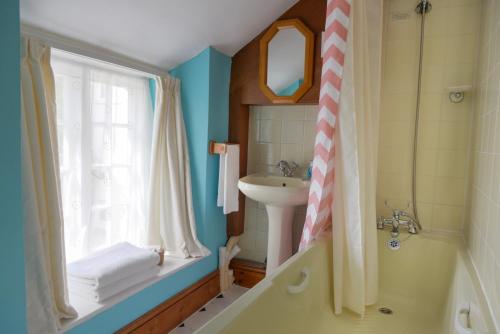 un bagno con lavandino e doccia con finestra di Ammonite Lodge a Chard