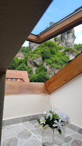 a vase with flowers sitting on a table in front of a window at Pension-Puttlachtal in Pottenstein